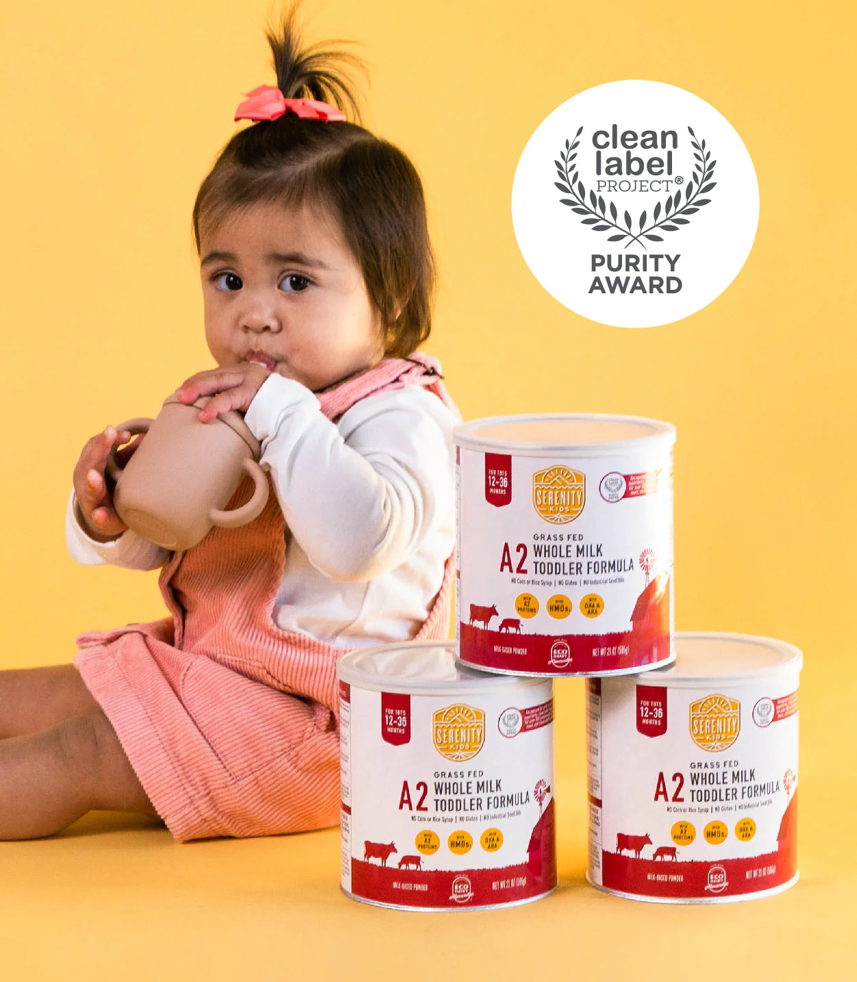 a little girl sitting on the floor with four cans of baby formulas