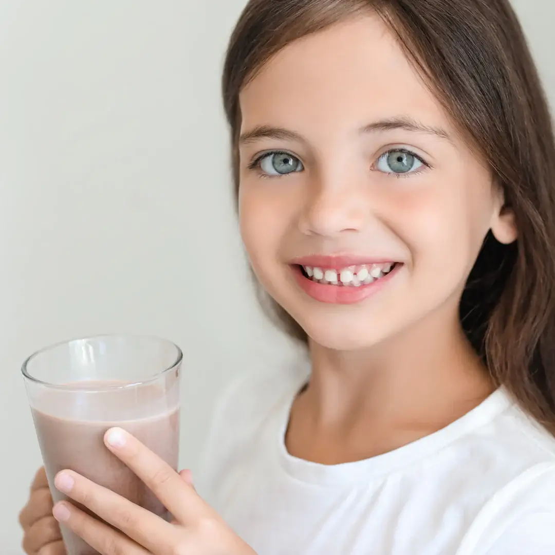 a young girl holding a glass of milk