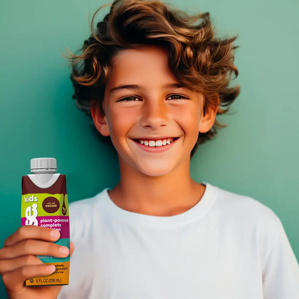 a young boy holding a bottle of chocolate milk