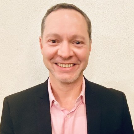 a man in a suit and pink shirt smiling