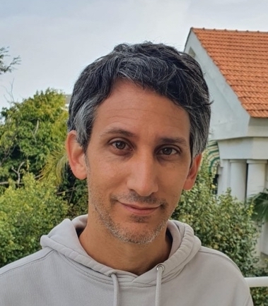 a man in a gray hoodie standing in front of a house