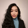 a woman with long black hair wearing a blue turtle neck sweater
