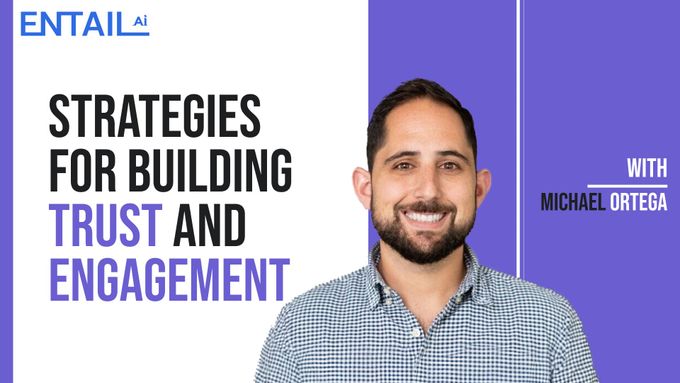 a man with a beard smiles in front of a purple and white background
