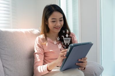 A woman sitting on a couch working on a tablet