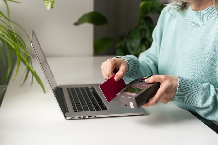 Woman using payment card terminal to shop online with credit card