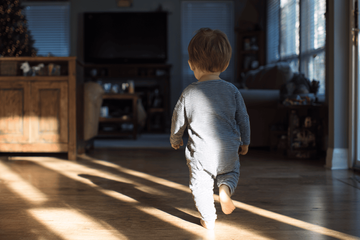 A little boy that is walking in a room barefoot because he has flat feet.