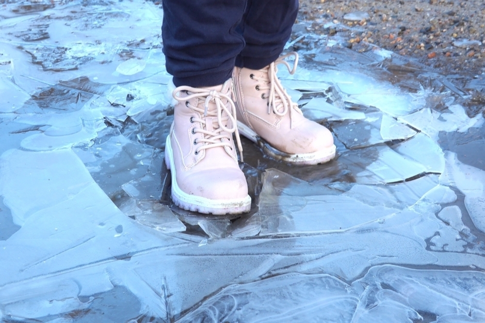 A child standing on ice wearing winter boots