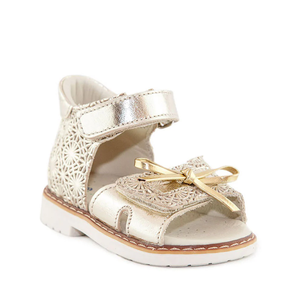 a little girl's white and gold shoe with a bow