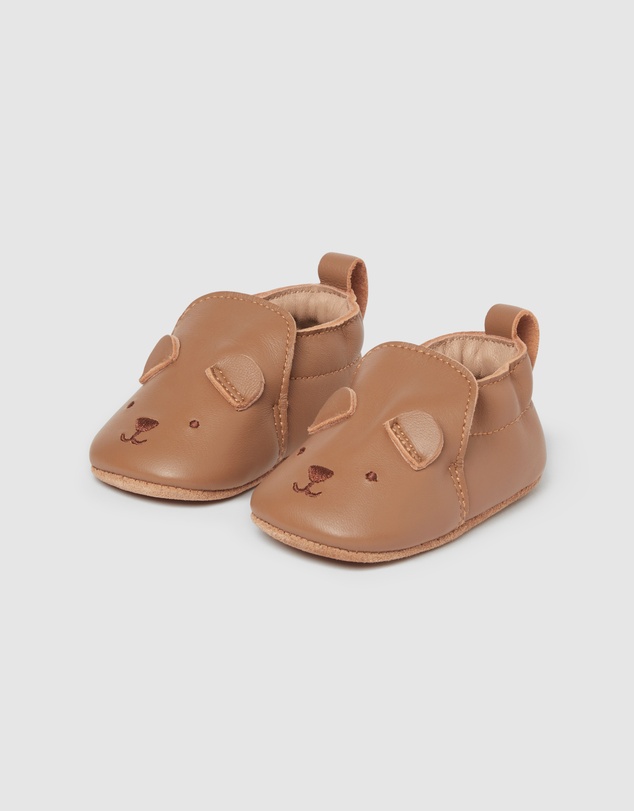 A pair of baby shoes with a bear face.