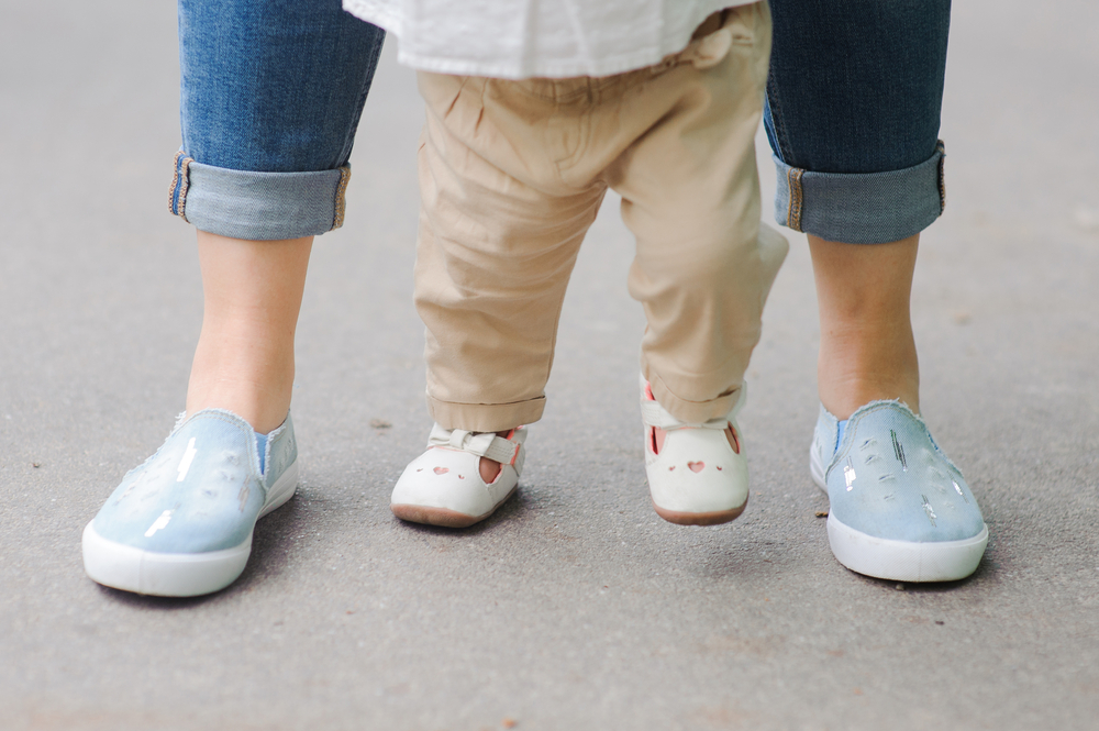 A child taking first steps with parent's support