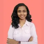 a woman standing with her arms crossed in front of a pink background