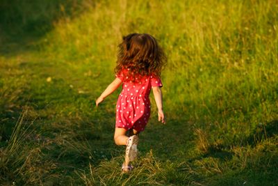 A baby girl running while wearing closed-toe sandals.