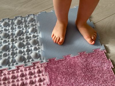 Baby sweaty feet: a child standing on a mat on the floor.