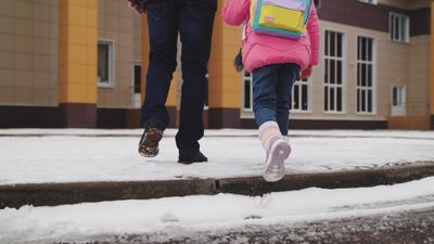 A little girl going to school wearing winter boots.