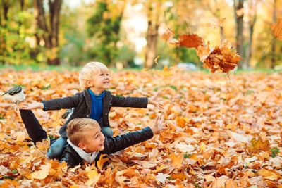 Two toddler boys are playing in the leaves -Best Kids Sheepskin Boots and Sneakers 