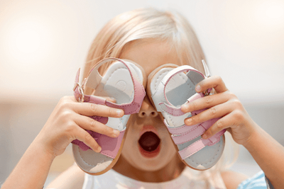 A little girl holding supportive sandals.