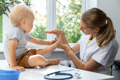 A podiatrist checking a toddler's foot.