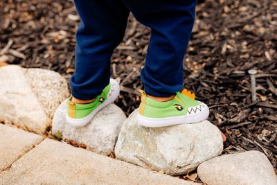 Child wearing green dinosaur kids' shoes.