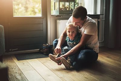 A dad helping his kid break in new shoes.