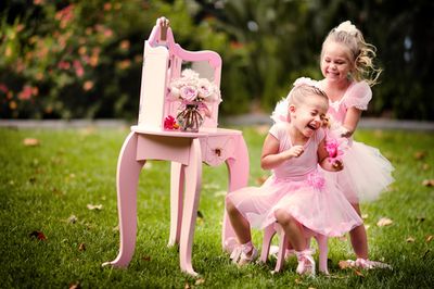 Two little girls in pink dresses playing in the grass - Top 5 Cute Pink Shoes for Little Girls
