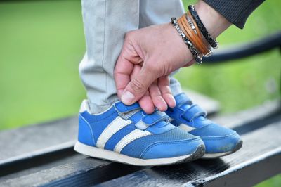 A pair of blue Velcro shoes being secured by the parent to child's feet