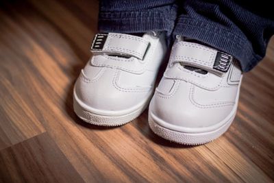 A little boy wearing white sneakers with Velcro straps for ease.