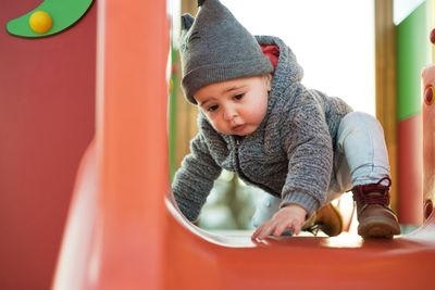 A toddler playing on a slide at a playground.