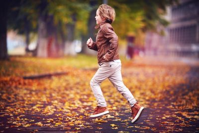 A young boy running through the park wearing arch support shoes.