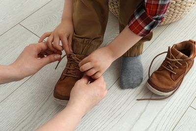 A parent helping their child put on orthopaedic shoes.