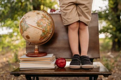 A child standing on a table with a globe and books.