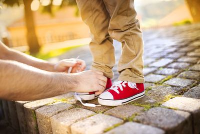 a father tying a pair of red tennis shoes