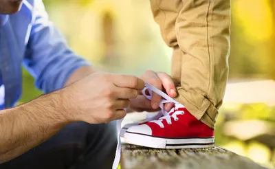a man tying a pair of red sneakers