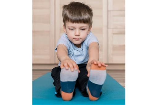 A young boy is sitting on a blue mat.