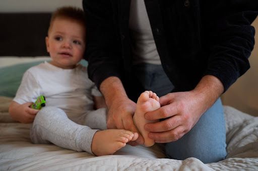 a man holding a baby's foot while sitting on a bed