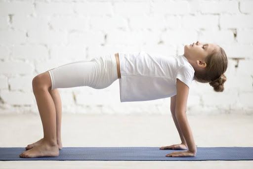 a woman in a white shirt is doing a yoga pose