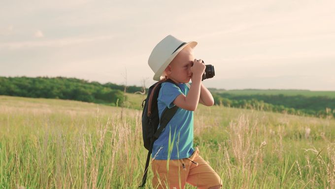 a young boy in a field with a camera