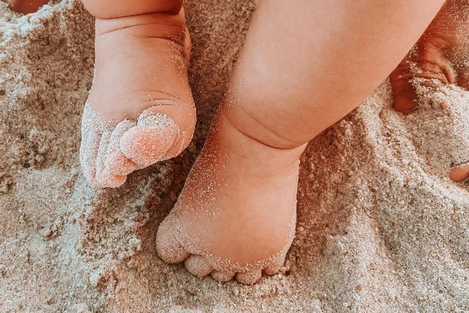 A close up of a child's feet covered in sand.