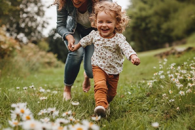 A toddler learning how to run with their mom.