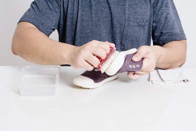 A man cleaning a shoe in an attempt to prevent plantar warts in his child