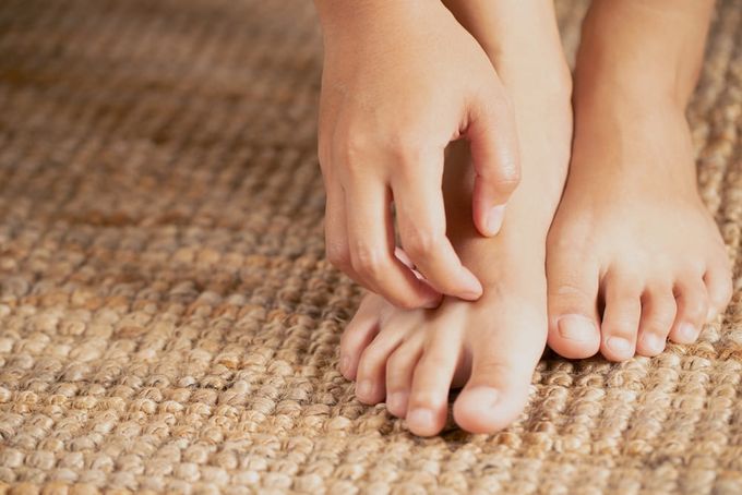 A close up of a person's bare feet on a rug.