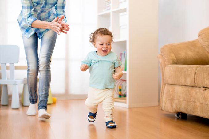 A toddler running indoors with shoes on to protect feet from injuries.