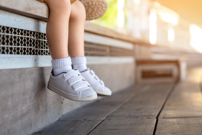A child wearing shoes sitting on a bench