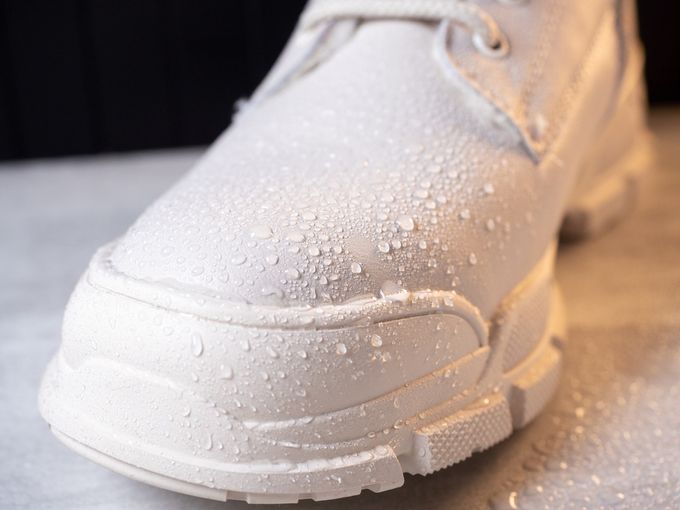Closeup view of water droplets on white color winter shoe protected with waterproof spray