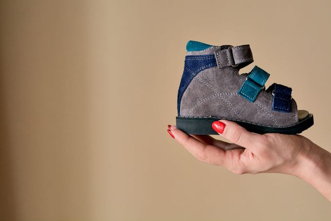 A woman's hand holding an orthopaedic shoe, a non-toy gift idea for a kid.