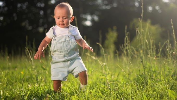 A little boy that is standing in the grass.
