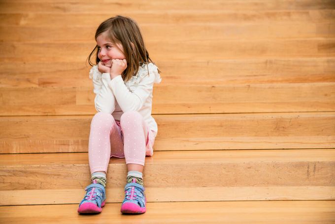 A girl is sitting on the stairs, wearing high-cut sandals with ankle support