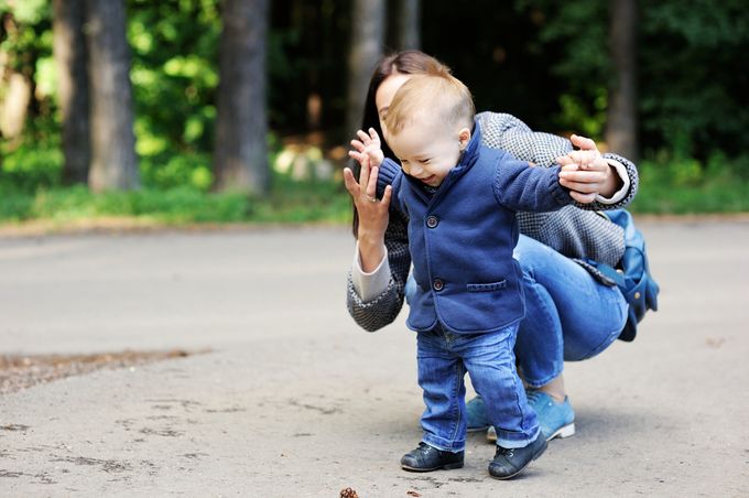 Vaby boy in blue coat makes his first steps in First Walkers shoes