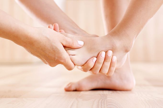 A woman doing stretching exercises on a child's foot to alleviate pain.