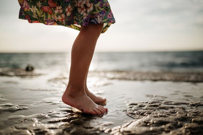 A toddler playing barefoot on the beach.
