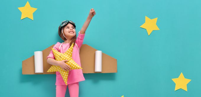 A little girl standing on top of a cardboard plane, letting her imagination take off - Stylish Children's Shoes With Animated Designs